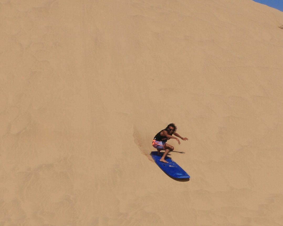 Walking up the dune, board under the arm