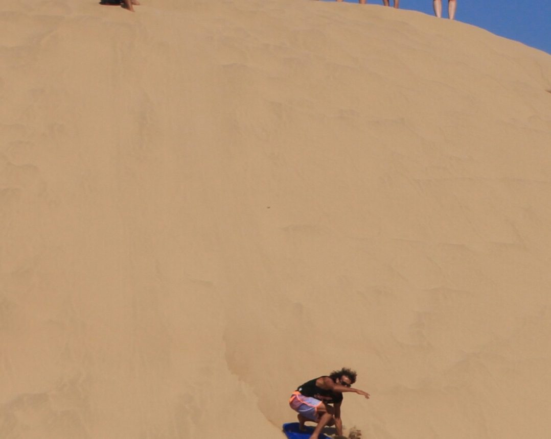 Sandboarding down the dunes near Tamraght