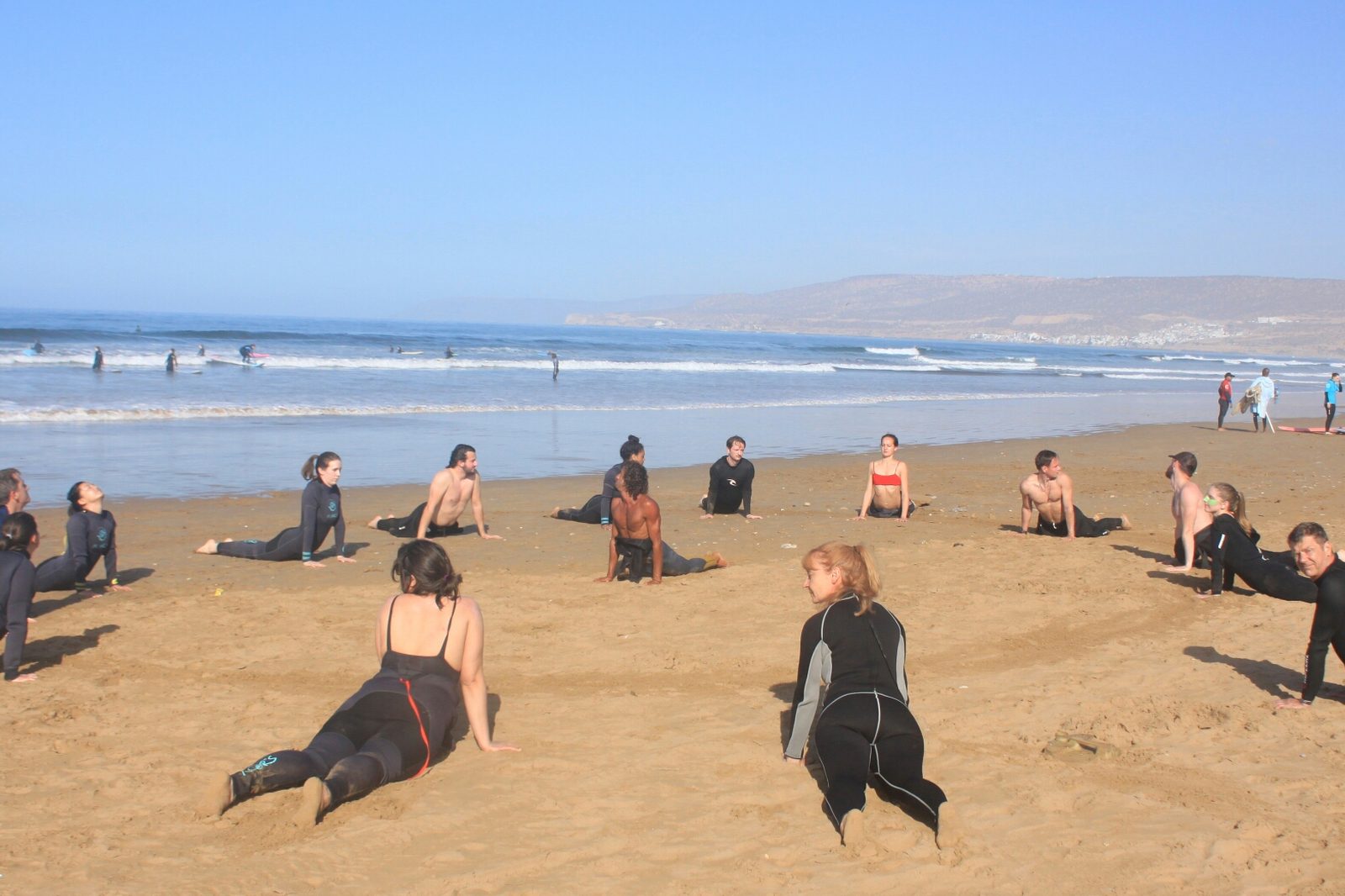 Surfers warming up on the beach, the Taghazout bay behind